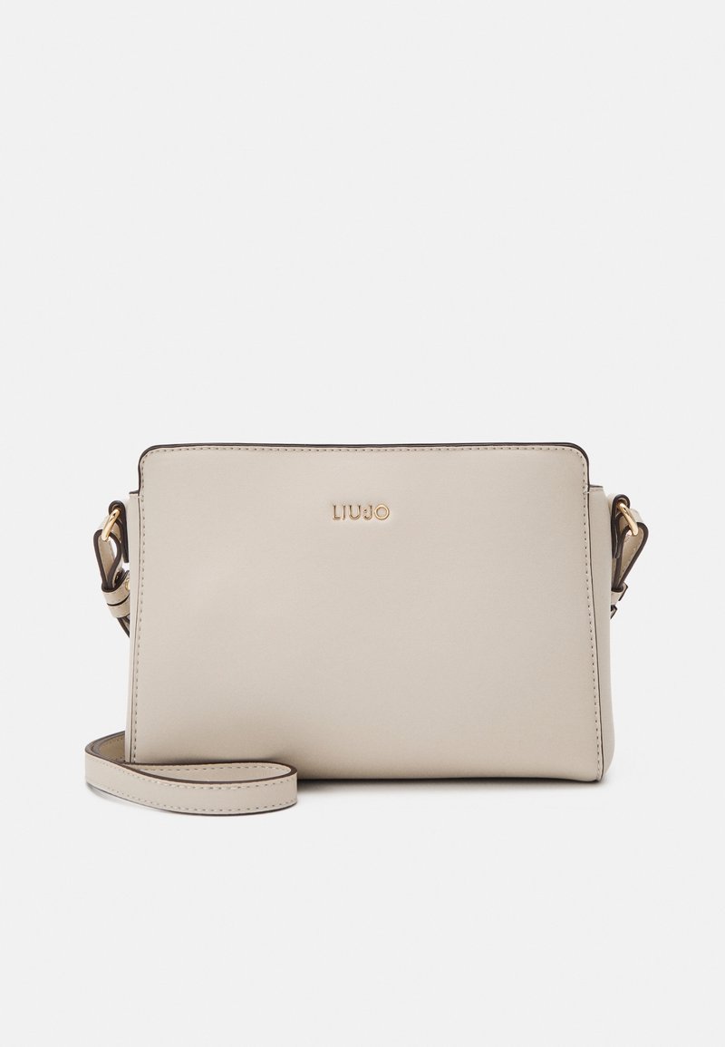 Bolso cruzado de cuero beige con una textura suave, forma rectangular, acentos de hardware dorado y una correa removible. Diseño y marca minimalistas.