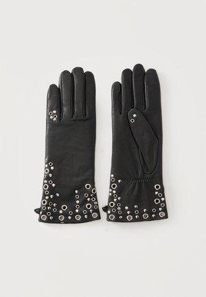 Par de guantes de cuero negro con detalles de ojales plateados pequeños y grandes a lo largo de los puños sobre un fondo claro y liso.