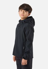 Boy wearing a black zip-up hooded jacket and black pants, standing sideways with a neutral expression against a plain background.