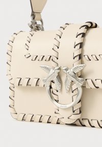 Beige bőr táska fonott mintával, ezüst színű madár alakú záróval és kontrasztos varrással. Kompakt, téglalap alakú.