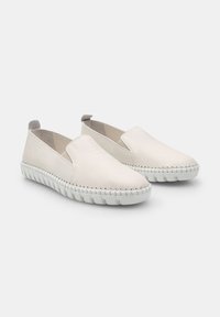 Fehér slip-on cipők sima bőr külső résszel, varrott részletekkel és texturált gumitalppal, amely a kényelmet és a könnyű viseletet szolgálja.
