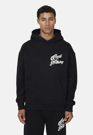 Hoodie noir en coton avec poche avant, présentant le texte blanc "Good for Nothing" sur la zone gauche de la poitrine et des poignets côtelés.