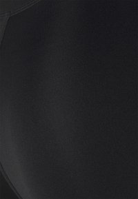 Leggings neri con una superficie liscia e strutturata caratterizzata da una leggera costina; vita elastica per comfort e vestibilità. Nessun motivo di design visibile.