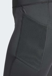 Leggings deportivos negros con un bolsillo de malla texturizada, costuras planas y un diseño ajustado para flexibilidad y comodidad.
