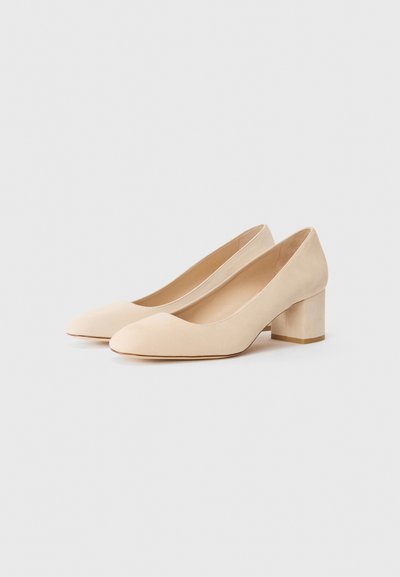 Pantofi cu toc bloc din suede bej, cu vârful rotund și o textură netedă. Tocurile sunt scurte și groase, oferind stabilitate.