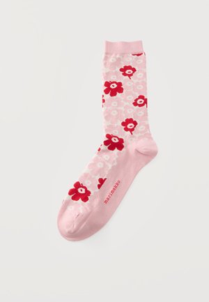 Един розов чорап с червено и бяло флорално вълнение и текст "marimekko" на подметката на бял фон.