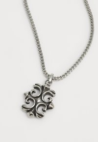 Collana in argento con un pendente decorativo caratterizzato da un motivo vorticoso e punte accentuate, realizzato in metallo lucido.