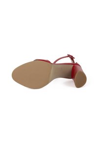 Punaiset korkokengät, joissa on sileä nahkapinta, ohut nilkkavyö ja beige tekstuuroitu kumipohja. Korko on tyylikäs ja pyöristetty.