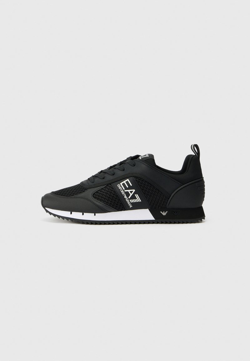 Baskets basses noires avec panneaux en mesh, lacets à l'avant, bande blanche sur la semelle intermédiaire et logo « EA7 Emporio Armani » sur le côté.