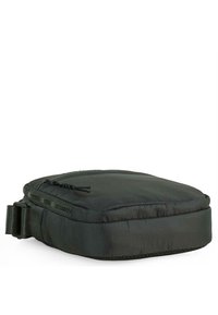 Funda de nailon negro con cierre de cremallera, forma rectangular aplanada y superficie texturizada. Incluye un accesorio de hebilla lateral para asegurar.