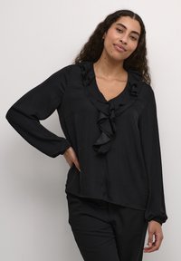 Black long-sleeve blouse featuring a ruffled neckline and cuffs, made of a lightweight fabric with a smooth texture.