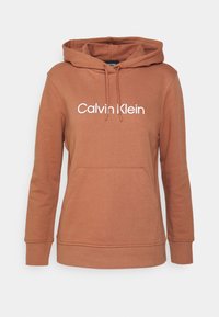 Brun hættetrøje med en frontlomme, der har "Calvin Klein" logo i hvid. Lavet af blødt, tekstureret stof med ribbede manchetter.