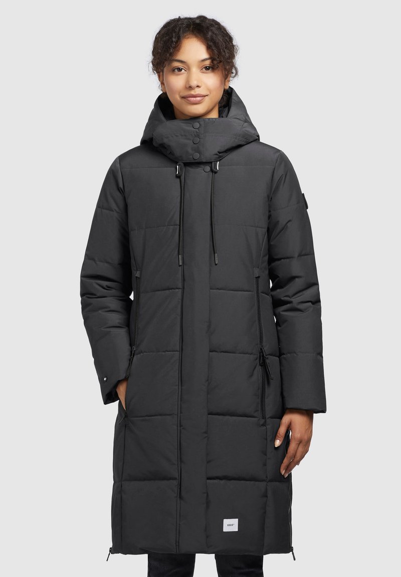 Black puffer coat with a hood, quilted design, zippered side pockets, adjustable drawstring closure, and a branded label on the hem.