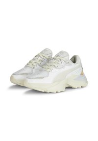 Białe sneakersy z teksturowaną cholewką, gładkimi akcentami i masywną, lekko podniesioną podeszwą. Posiadają sznurówki oraz perforowane detale na palcach.