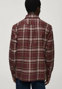 Camisa a cuadros burdeos con patrón de cuadros blanco y amarillo, con collar de botones y mangas largas, que presenta un yugo trasero y costuras laterales.