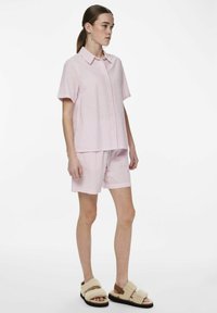 Set composto da camicia a maniche corte a righe rosa e bianche e pantaloni coordinati, realizzato in tessuto leggero. Presenta una vestibilità comoda e un'apertura frontale con bottoni.