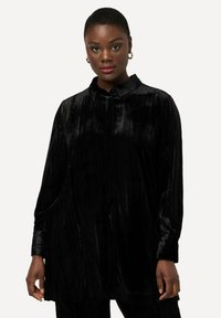 Camicia in velluto nero con colletto, maniche lunghe e vestibilità ampia. Presenta una trama verticale e chiusura con bottoni.