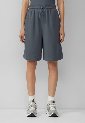 Gray cotton blend shorts with a drawstring waistband, side pockets, and a loose fit, paired with silver athletic shoes and white crew socks.