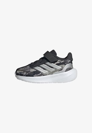 Baskets à motif camouflage noir et gris avec trois bandes argentées, une bride noire en velcro et une semelle blanche épaisse.