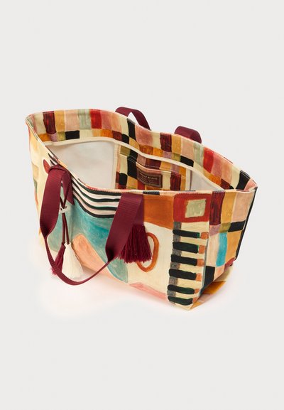 Τσάντα ώμου από καμβά με πολύχρωμα αφηρημένα σχέδια. Διαθέτει χέρια και φούντες σε βουργουνδί απόχρωση και ευρύχωρο εσωτερικό.