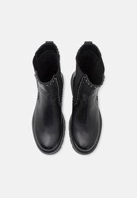 Botas de tobillo de cuero negro con paneles laterales elásticos, acentos de tachuelas, punta redondeada y suela texturizada. Acabado suave y detalles de costura en contraste.