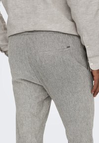 Grijs gestreepte broek gemaakt van een gestructureerde stof, met een verborgen zak op de achterkant en een recht-toe-rechtaan ontwerp.