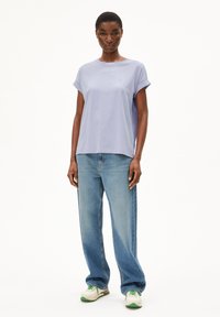 Light purple cotton T-shirt with short rolled sleeves, paired with loose blue denim jeans and white-green sneakers.