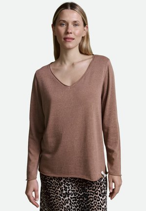 Long-sleeve, v-neck top in a soft, muted brown knit fabric. The hem is slightly curved, paired with a patterned animal-print skirt.