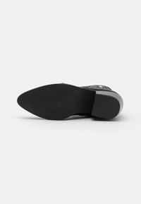 Czarna podeszwa buta o gładkim, zaokrąglonym kształcie. Teksturowana guma zapewniająca przyczepność, z delikatnymi żłobieniami w rejonach palców i pięty.