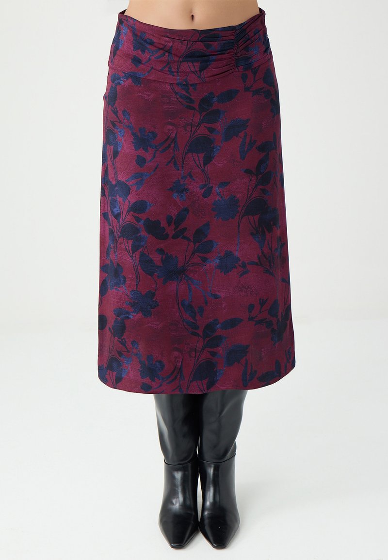 Bordeauxfarbener Rock mit dunkelblauem Blumenmuster, glatter Textur, knielang, mit einem gerafften Bund. Schwarze Stiefel mit Absatz darunter.