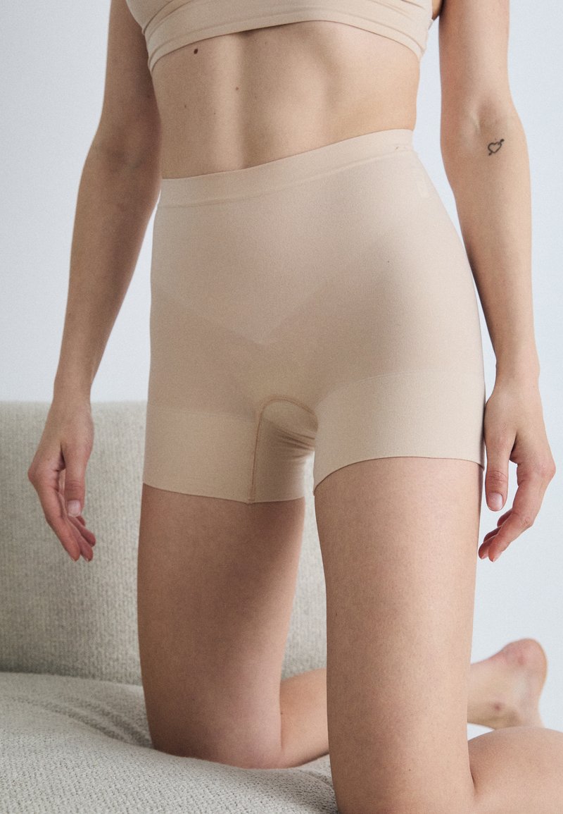 Beige seamless shorts made from a soft, stretchy material with a mid-rise waistband and a smooth texture, featuring no visible seams.