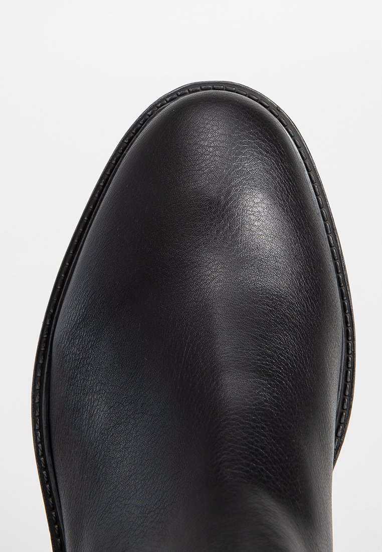 Embout de chaussure en cuir noir poli avec des coutures détaillées autour du bord de la semelle sur un fond blanc uni.