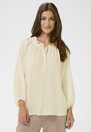 Svetložltá blúzka s volánikovým výstrihom a zaväzovaním, s dlhými rukávmi a mierne textúrovanou, pruhovanou tkaninou.