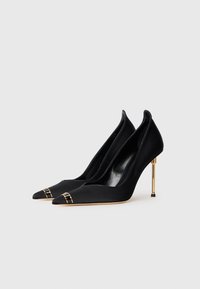 Black satin high-heeled shoes with a pointed toe, featuring gold accents at the toe and a unique gold heel detail. Smooth texture.