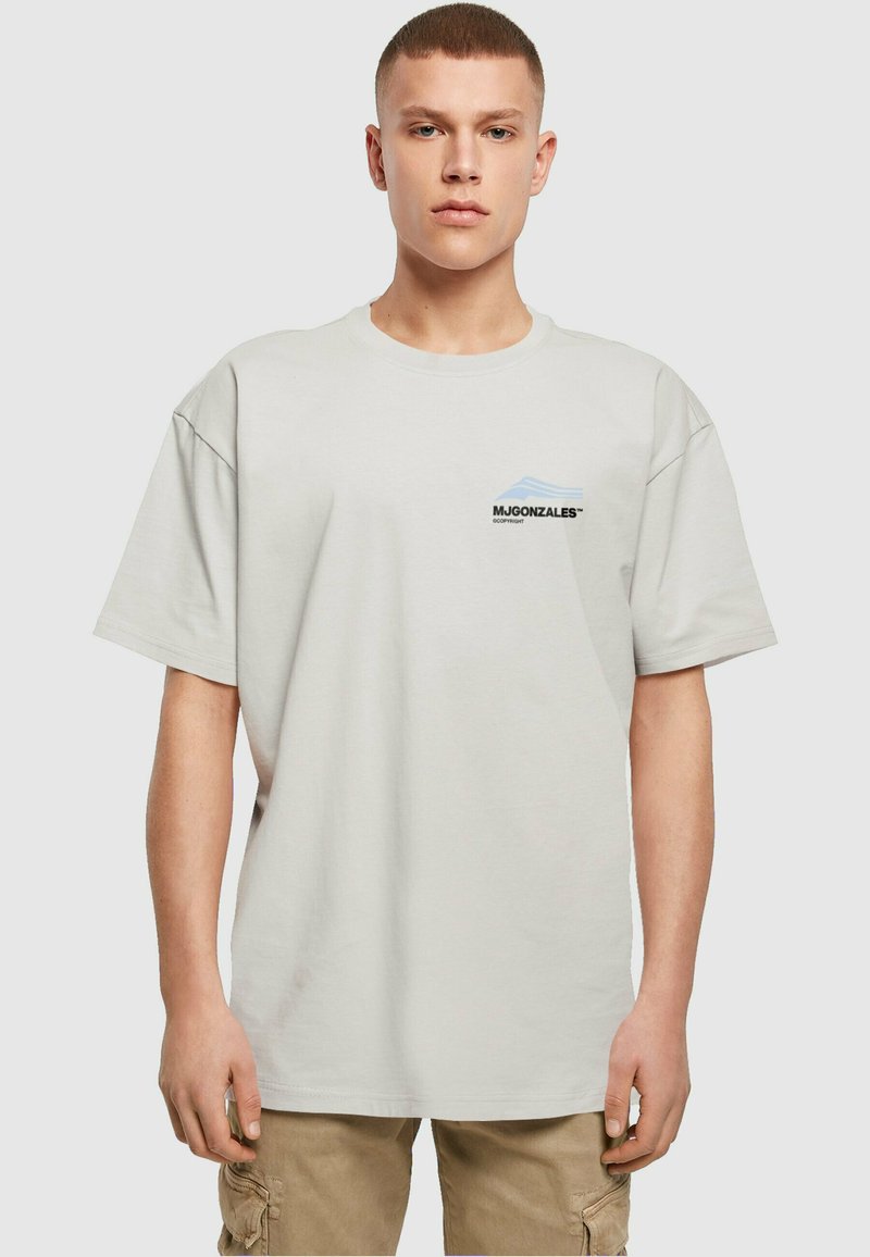 Világosszürke oversized pamut póló, bal mellen kis fekete és kék logóval. Rövid ujjak és kerek nyakú kialakítás.