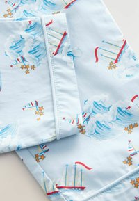 Tela de color azul claro con un patrón de veleros, nubes y estrellas. El diseño incluye acentos en rojo y azul con una textura suave.