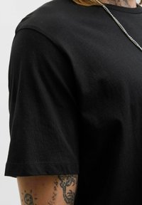 Schwarzes Baumwoll-T-Shirt mit kurzen Ärmeln und rundem Ausschnitt, das eine glatte Textur und subtile Nähte aufweist.