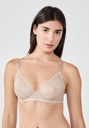 Lace bralette in nude color with a triangular shape, scalloped edges, adjustable straps, and floral lace pattern. Soft texture.