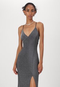 Rochie de seară gri cu sclipici, cu decolteu în V, bretele subțiri, croi ajustat, fente laterală și textură netedă. Design elegant și adaptat corpului.