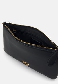 Juoda odinė pouch tipo rankinė su auksine užtrauktuku, turinti tekstūruotą išorę ir lygią pamušalą. Apima vidinį užtrauktuką kišenėje organizavimui.