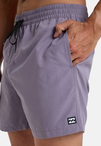 Shorts de bain violets en tissu léger, dotés d'une taille élastique, d'un cordon de serrage ajustable et d'une poche latérale avec logo.