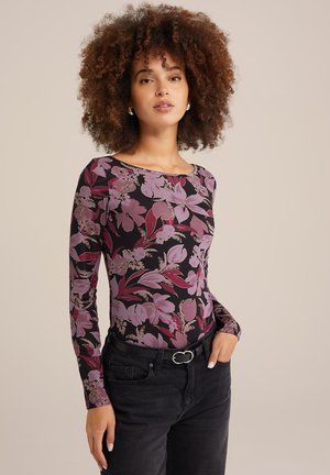Long-sleeve top in black fabric featuring pink floral patterns. Round neckline and slim fit, paired with dark jeans and a belt.