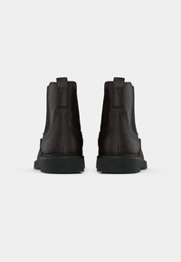 Black leather ankle boots with smooth texture, elastic side panels, and rubber soles. Features pull tabs for easy wear.