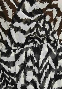 Tessuto a righe in bianco e nero con un design ondulato e una texture a pennellate, sovrapposto a pieghe e diverse tonalità di grigio.