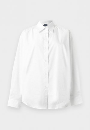 Λευκό μακρυμάνικο πουκάμισο με κουμπιά και μυτερό γιακά, απλωμένο επίπεδα σε απλό λευκό φόντο.
