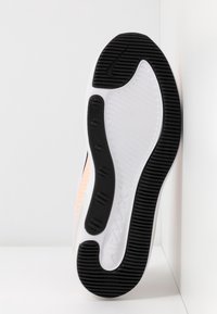 Semelle d'une chaussure Nike Air Max blanche et noire avec une adhérence texturée et un logo visible sur une surface blanche.