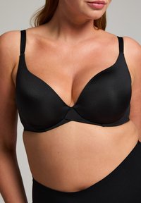 Zwarte beugelbh van glad, glanzend materiaal, met een diepe halslijn en verstelbare bandjes. Beschikt over een naadloos ontwerp, geschikt voor verschillende outfits.