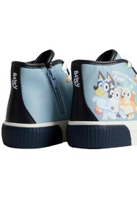 Modré a tmavě modré vysoké tenisky s texturovanou gumovou podrážkou, které mají grafiku kresleného psa a boční zipové zapínání.