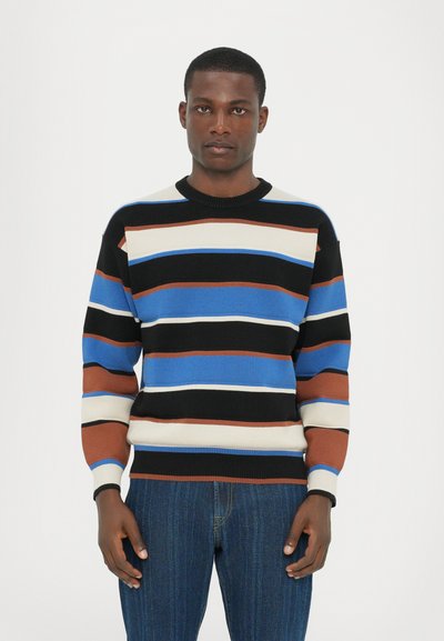 Strickpullover mit horizontalen Streifen in Blau, Schwarz, Braun und Creme. Abgeschlossen mit einem gerippten Halsausschnitt und Saum. Getragen mit dunkler Denim.