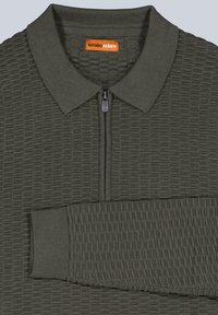 Dunkelgrünes Zip-Polo mit strukturiertem Oberflächenmaterial, geripptem Kragen und Ärmeln. Besitzt dezente, erhabene Muster, die sich über den Stoff ziehen.